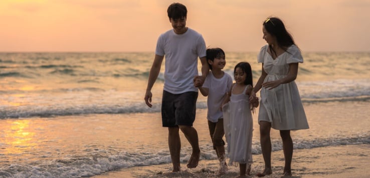 Asian family walking on beach during sunset