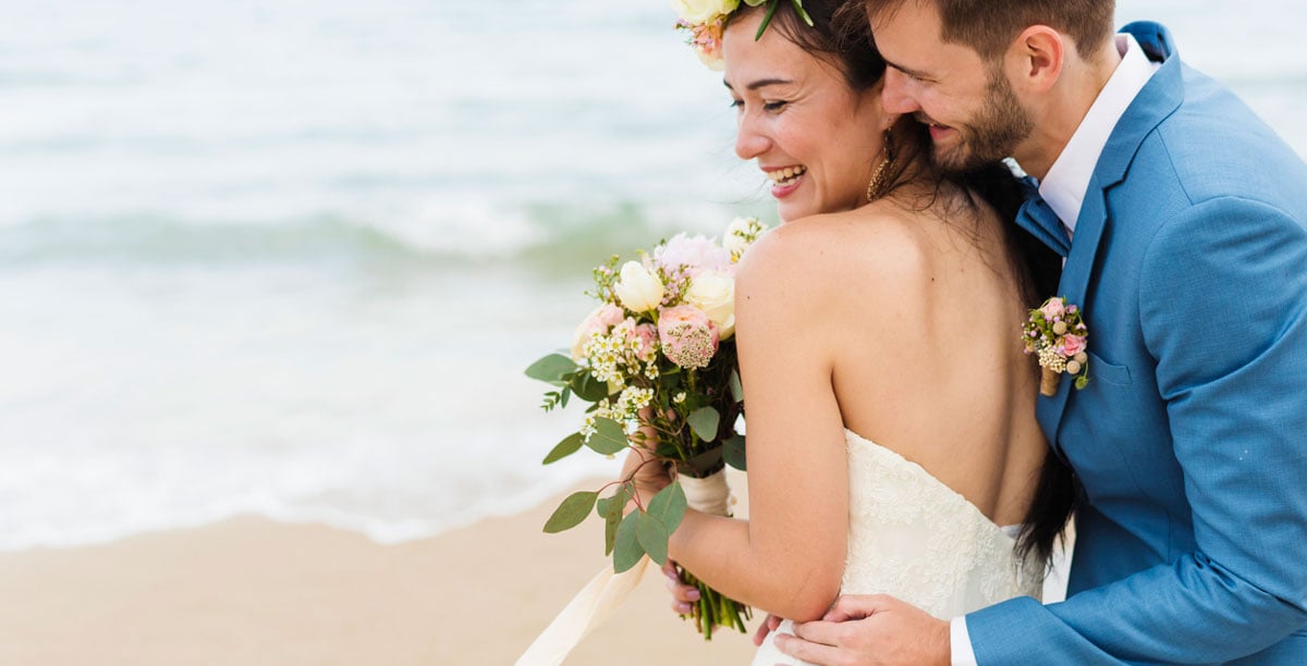 Cheerful newlyweds at beach wedding ceremnoy