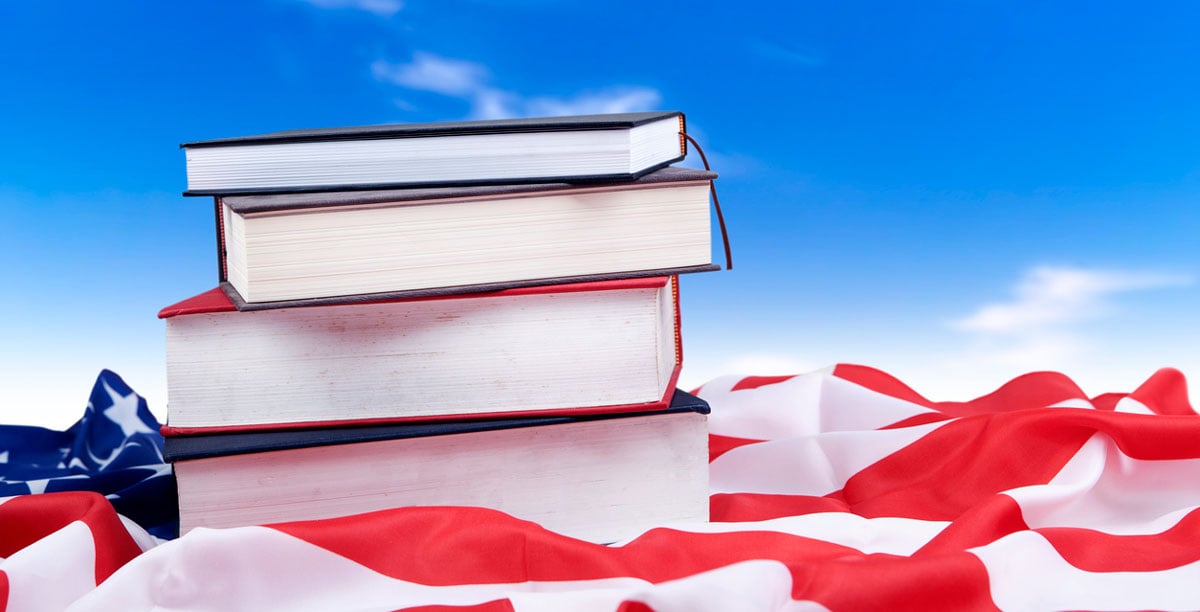 Stack of books laying on top of American flag 