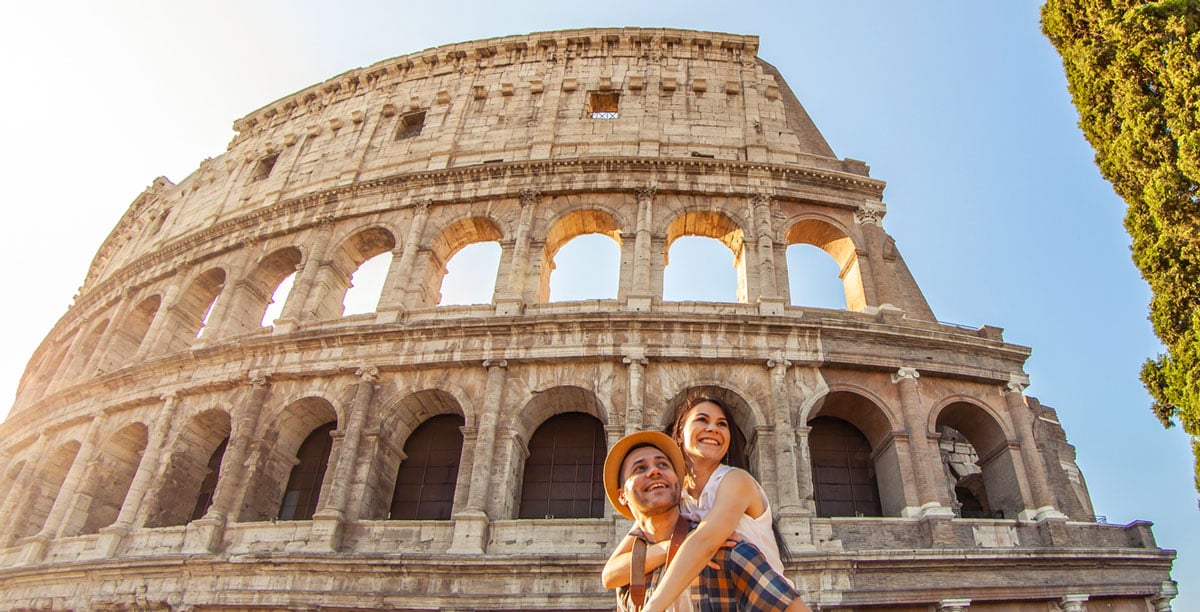 Young couple piggyback posing at Colosseum in Rome