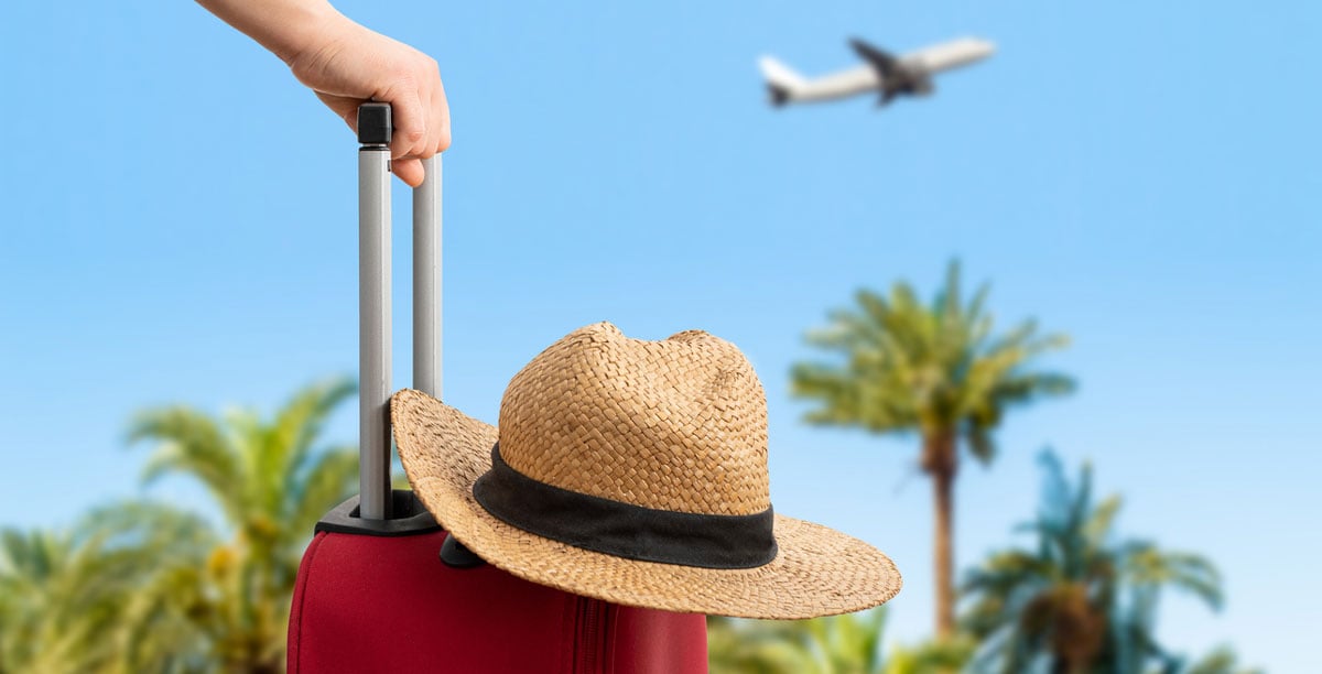 Hat resting on suitcase with views of palm trees and airplane