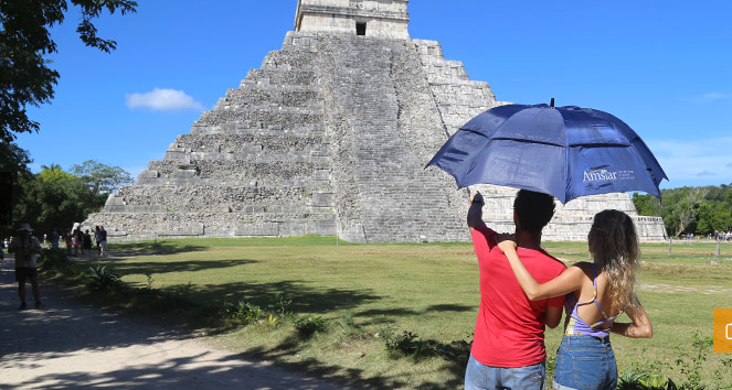 Couple under umbrella staring at Chichen Itza